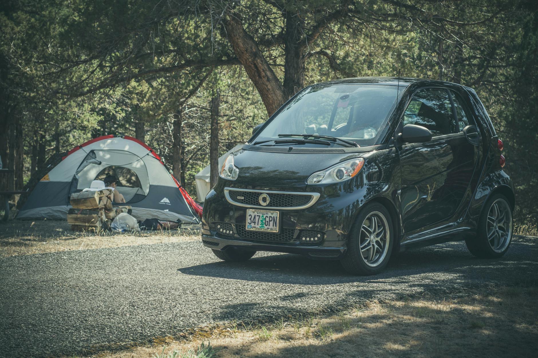 Mały samochód i namiot na leśnym kempingu podczas weekendowego wyjazdu