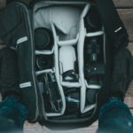Sprzęt fotograficzny w plecaku na drewnianej podłodze