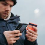 Mężczyzna wpisuje dane karty kredytowej w telefonie podczas płatności