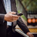 Mężczyzna w garniturze korzysta ze smartfona w trakcie pracy w mieście