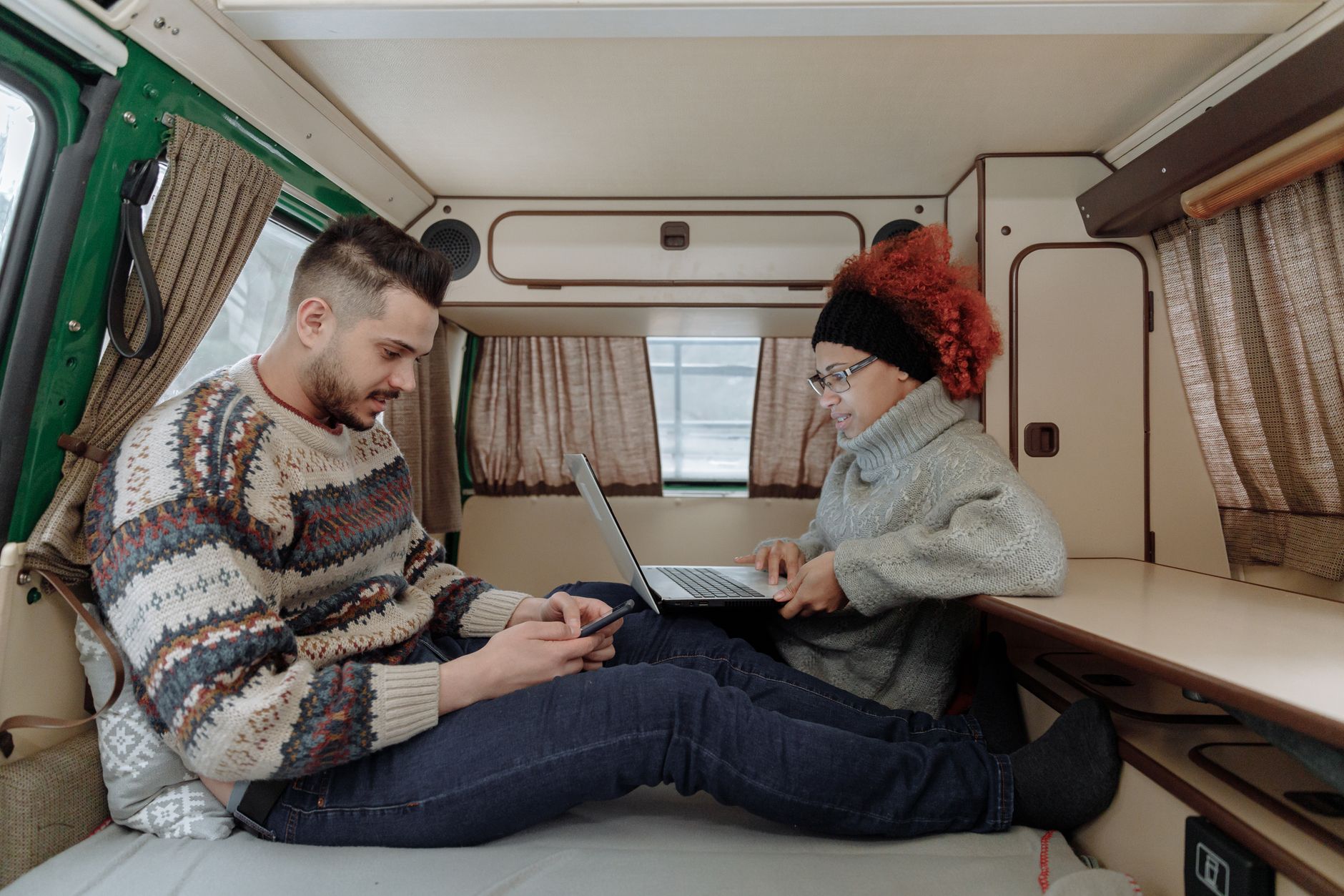 Para pracująca na laptopie i smartfonie w kampervanie podczas podróży