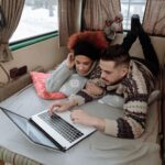 Para w kampervanie z laptopem pracuje w przytulnym wnętrzu