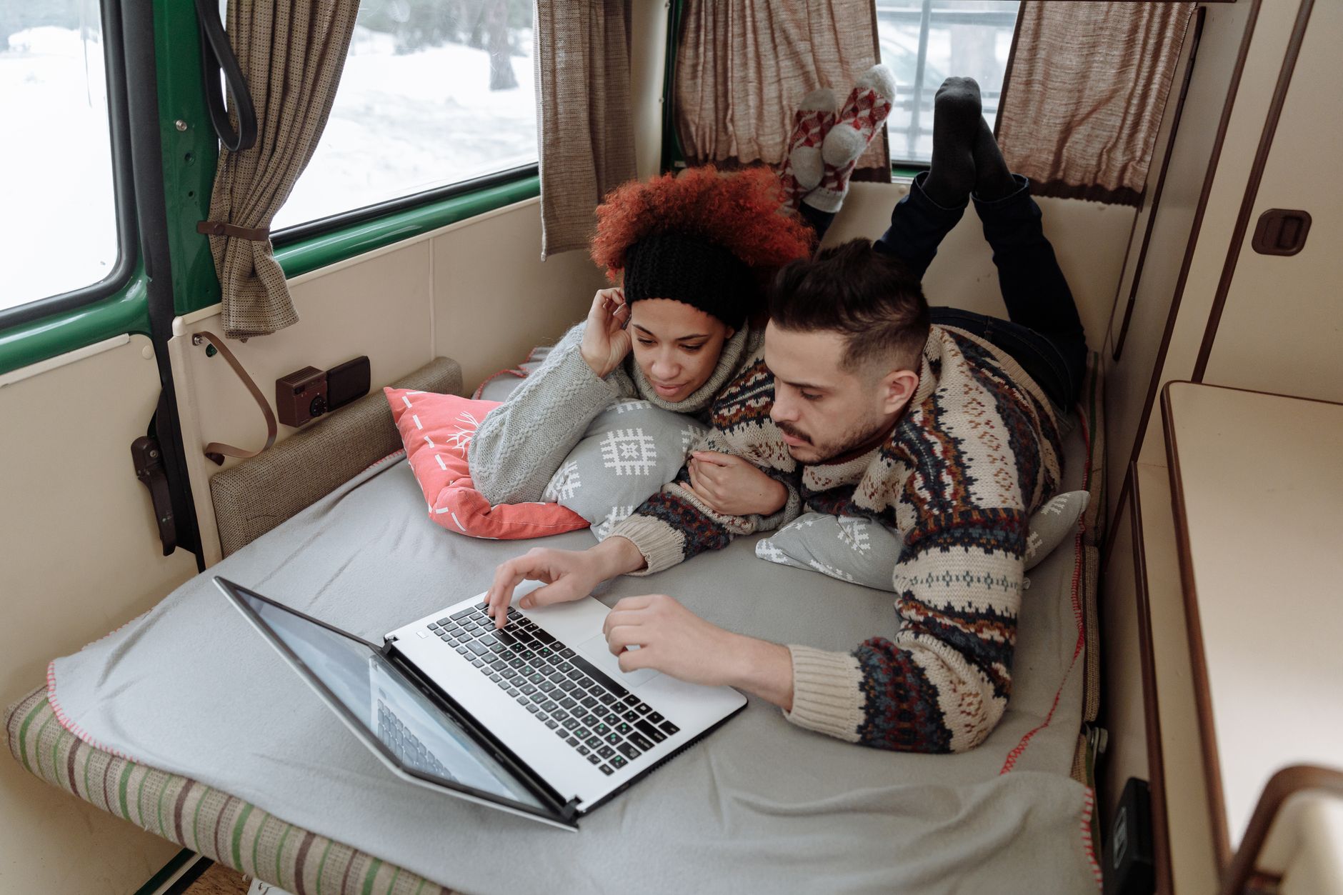 Para pracująca na laptopie i smartfonie w kampervanie podczas podróży