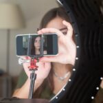 Młoda kobieta korzysta ze smartfona z lampą pierścieniową w domu