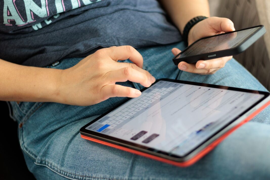 Zbliżenie na osobę korzystającą z tabletu i smartfona w domu